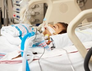 Hispanic boy in Intensive Care Unit bed