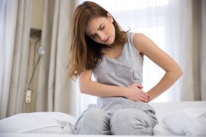 woman sitting on the bed with pain